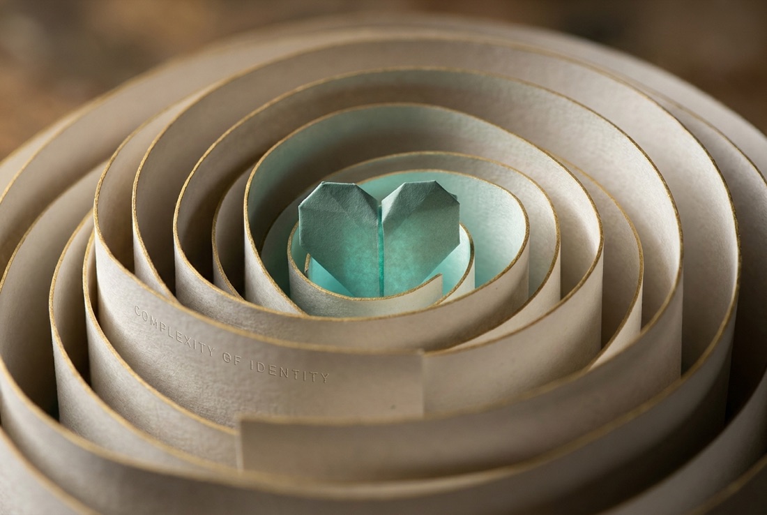 A spiral of folded paper winding inward to a teal heart center